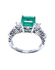 An emerald ring square emerald on top and side princess cut diamonds in whit gold.
