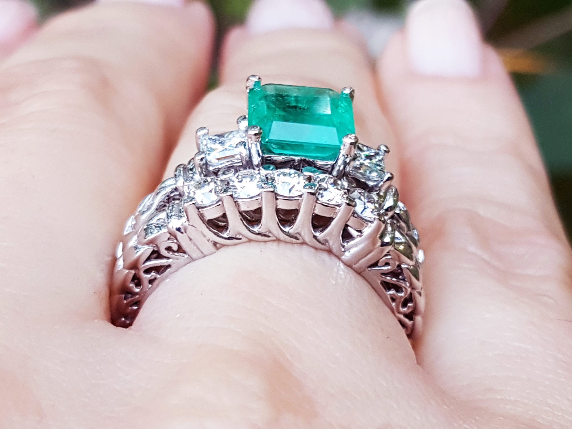 The gallery view of a diamond wedding match band of an emerald engagement ring on a person's hand.
