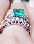 The gallery view of a diamond wedding match band of an emerald engagement ring on a person's hand.