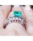 The gallery view of a diamond wedding match band of an emerald engagement ring on a person's hand.