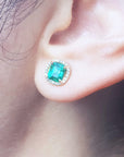 Close-up of an ear wearing a Muzo Colombian Halo emerald stud earring.