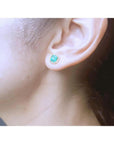 1.55 carat emerald stud earring with halo diamonds in 14K yellow gold on an ear.