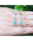 Deep bluish-green emerald marquise earrings in 14K gold with diamond lever backs, dangling from double marquise frames.