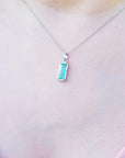 Necklace with a white gold emerald pendant on a person's chest
