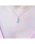 Colombian emerald solitaire pendant in 14K white gold, worn on a woman's neck.