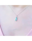 Colombian emerald solitaire pendant in 14K white gold, worn on a woman's neck.