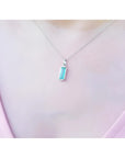 Colombian emerald solitaire pendant in 14K white gold, worn on a woman's neck.