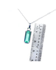 Rectangular emerald cut Colombian emerald solitaire pendant in 14K white gold with ruler for scale.