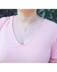 Colombian emerald solitaire pendant in 14K white gold, worn on a woman's neck.