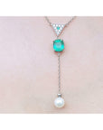 14K white gold necklace with emerald cushion cut, diamond triangle, and hanging white pearl.