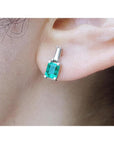 Colombian emerald and baguette diamond stud earrings, 14K white gold, on an ear.