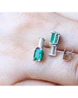 Colombian emerald and baguette diamond stud earrings in 14K white gold, featuring rectangular emerald-cut gems.