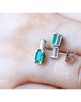 Colombian emerald and baguette diamond stud earrings in 14K white gold, featuring rectangular emerald-cut gems.
