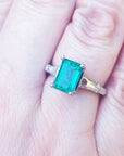 Ring with a natural emerald and baguette diamond for women on a finger.
