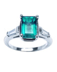 An emerald and baguette side diamond ring on a top and sides profile view with a white background