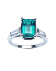 An emerald and baguette side diamond ring on a top and sides profile view with a white background