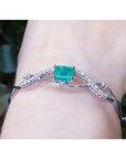 Emerald-cut emerald and natural diamond bangle bracelet in 14K white gold.