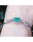 Emerald-cut emerald and natural diamond bangle bracelet in 14K white gold.