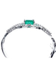 14K white gold bangle bracelet with a central emerald-cut green emerald and diamond accents.