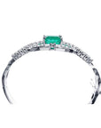 14K white gold bangle bracelet with a central emerald-cut green emerald and diamond accents.