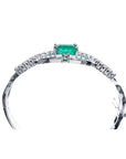 14K white gold bangle bracelet with a central emerald-cut green emerald and diamond accents.