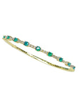 Flexible 14K yellow gold bangle bracelet with round emeralds and accent diamonds.