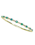 Flexible 14K yellow gold bangle bracelet with round emeralds and accent diamonds.