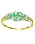 14K yellow gold bangle with round cut Colombian emeralds and diamonds in a floral design.