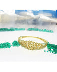 14K yellow gold bangle with round Colombian emeralds and diamonds in a floral design.