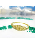 14K yellow gold bangle with round Colombian emeralds and diamonds in a floral design.