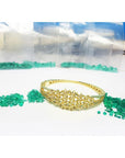 14K yellow gold bangle with round Colombian emeralds and diamonds in a floral design.