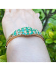 A side lateral view of a colombian emerald bangle bracelet on a wrist.