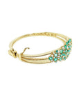 14K yellow gold bangle bracelet with round cut Colombian emeralds and diamonds in a floral design.