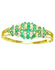 14K yellow gold bangle with round Colombian emeralds and diamonds in a floral design.