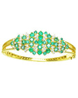 14K yellow gold bangle with round Colombian emeralds and diamonds in a floral design.