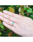 0.93 ct. solitaire emerald cut Colombian emerald ring in 14K yellow gold on a hand.