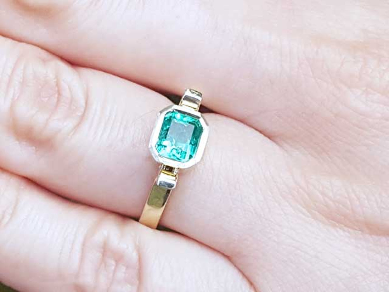 Gold ring with a colombian emerald gemstone on a hand