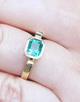 Gold ring with a colombian emerald gemstone on a hand