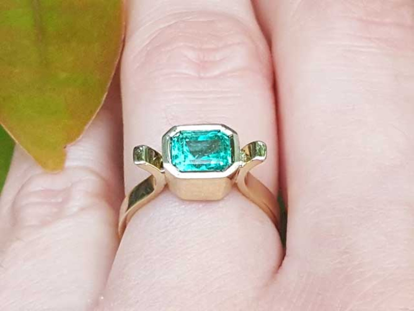 Gold ring with a natural emerald on a finger