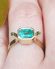 Gold ring with a natural emerald on a finger