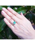 18K gold ring with a 2.10 ct emerald-cut bluish-green emerald and princess-cut bezel-set diamonds.