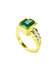 18K gold ring with a rectangular emerald-cut emerald and bezel-set princess-cut diamonds.