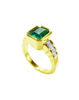 18K gold ring with a rectangular emerald-cut emerald and bezel-set princess-cut diamonds.