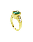 18K gold ring with a 2.10 ct emerald-cut emerald bezel set, flanked by three princess-cut diamonds.