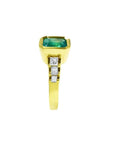 18K gold ring with a 2.10 ct emerald-cut emerald and three princess-cut diamonds bezel set on each side.