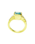 This bezel set emerald ring with accent princess cut diamonds is displaying its high top and lateral gallery.