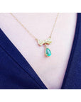 18K yellow gold bow-tie necklace with pave diamonds and a dangling pear-shaped emerald.