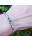 14K white gold bracelet with a rectangular Muzo Colombian emerald and diamond accents on a wrist.