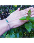 14K white gold bracelet with a rectangular Muzo Colombian emerald and six diamond accents on a woman's wrist.