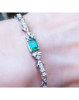 An emerald-cut Muzo Colombian emerald bracelet natural diamonds 14k white gold on a wrist.